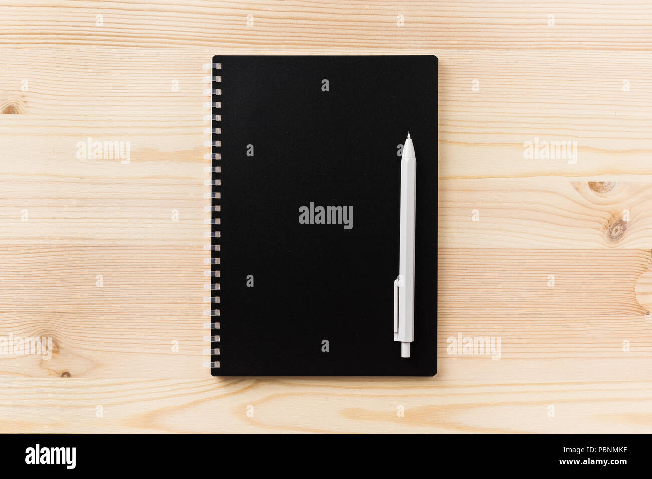 Design concept - Top view of black spiral notebook and wood pen on wood ...