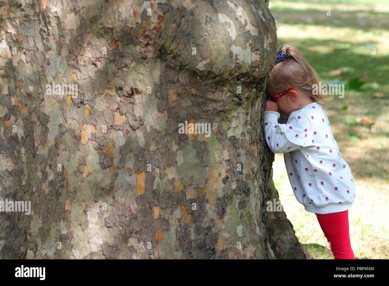concept of crying, sulking or playing hide and seek by a young girl Stock Photo
