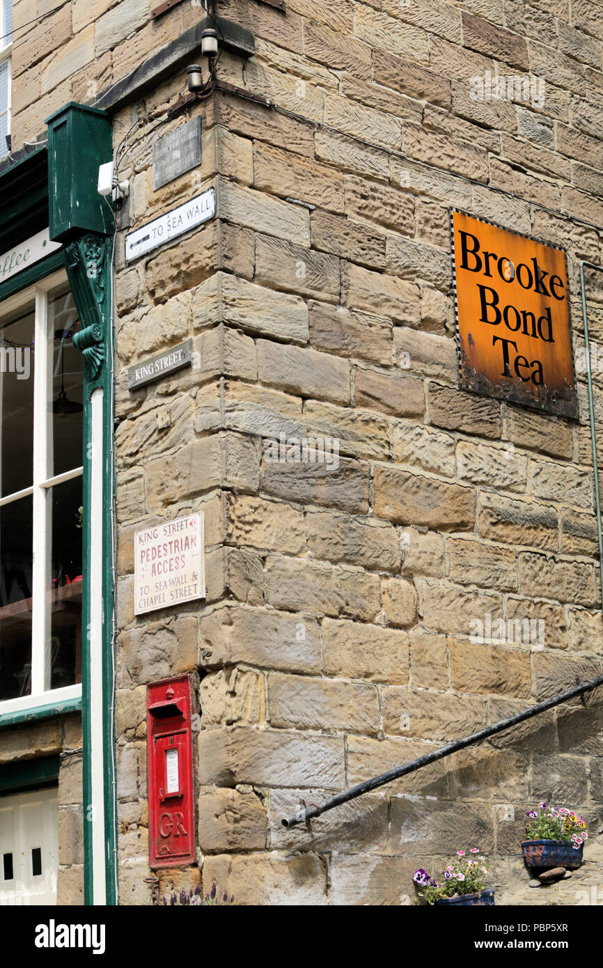 Corner of the old Post Office building in King Street, Robin Hood's Bay, showing post box and enamel Brooke Bond tea advertising sign Stock Photo