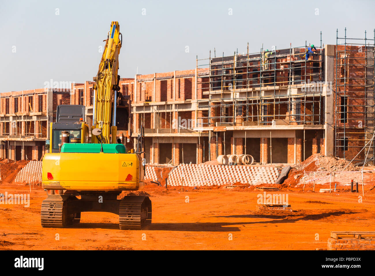 Construction apartments site of new building in progress with earthwork excavator machine. Stock Photo