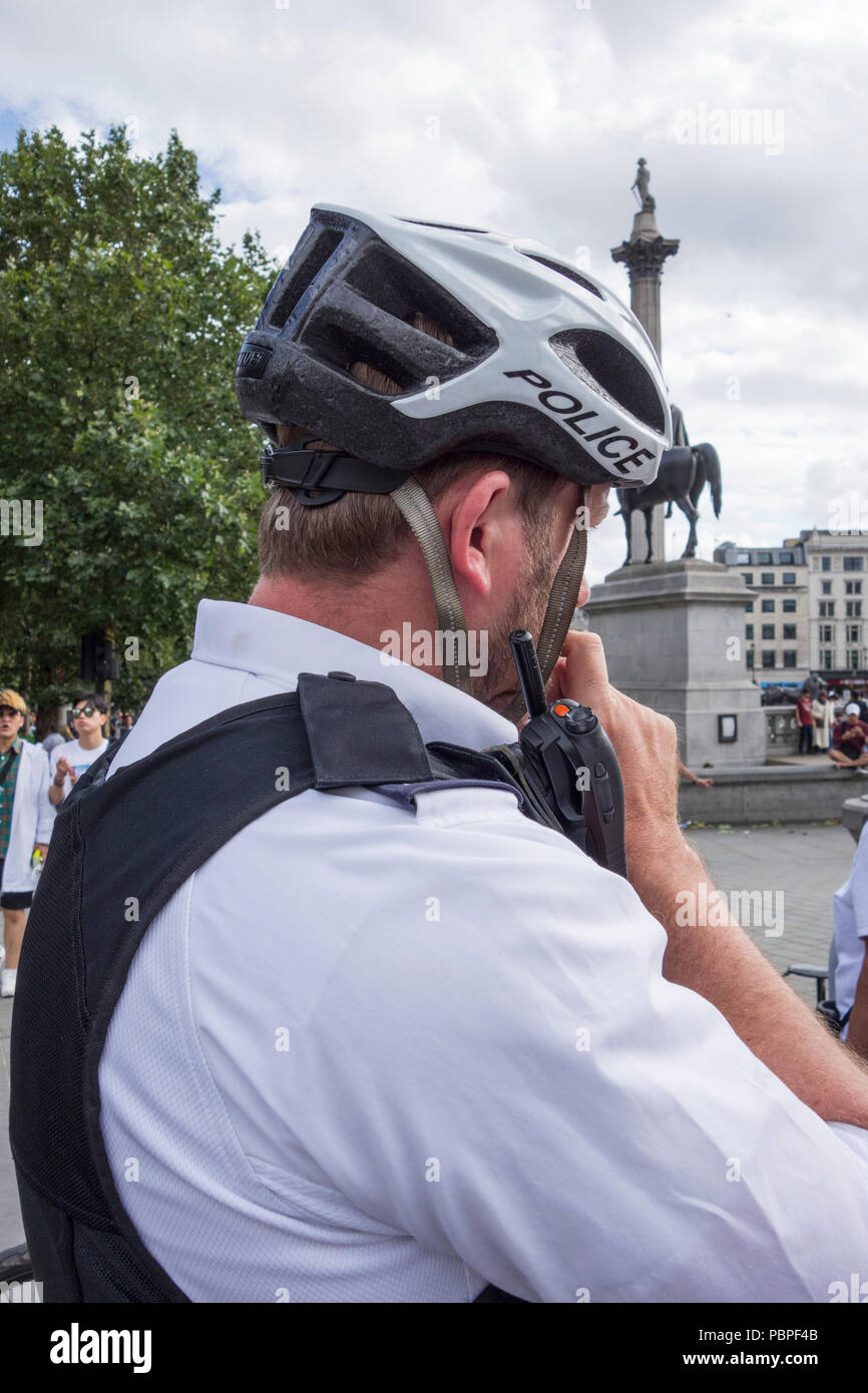 Police cyclist wearing protective headgear in Trafalgar Square, London, UK Stock Photo