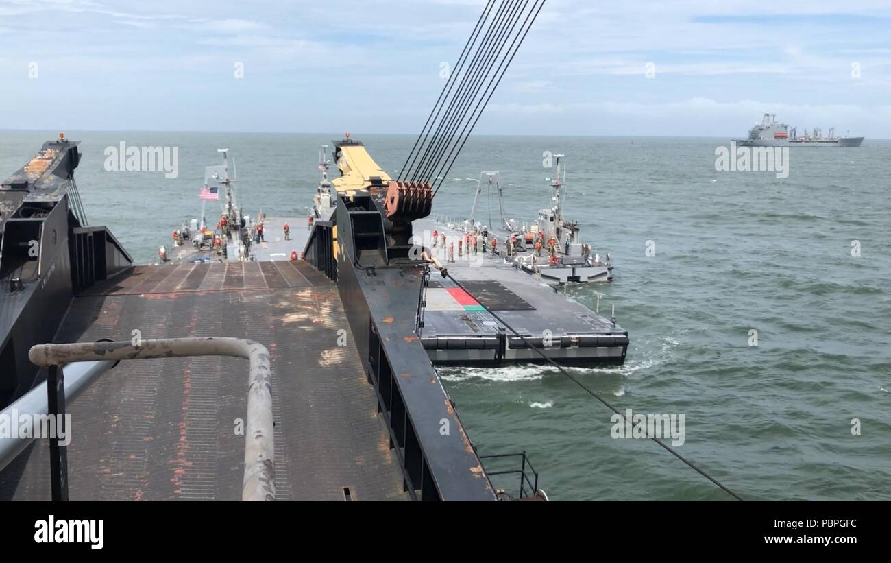 VIRGINIA BEACH, Va. (July 23, 2018) Sailors assigned to Amphibious Construction Battalion 2 use two Improved Navy Lighterage System Warping Tugs to position the Roll On/ Roll Off Discharge Facility platform underneath the rear ramp of the Military Sealift Command’s ship UNSN Eugene A. Obregon (T-AK 3006) during the Naval Beach Group 2 led Trident Sun 18 exercise. Trident Sun 18 is a Maritime Prepositioning Force (MPF) operation intended to provide training to reserve component personnel with regards to the in-stream offload of military vehicles and equipment. (U.S. Navy photo by Lt. Cmdr. Lara Stock Photo