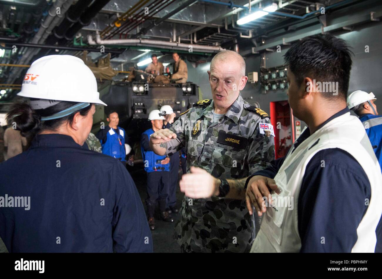 180723-N-VR594-1126 AT SEA (July 23, 2018) Royal Australian Navy Lieutenant Commander Gordon Jardine, assigned to Royal Australian Navy landing helicopter dock ship HMAS Adelaide (L01), speaks with Philippine Navy sailors after boarding assault amphibious vehicles (AAV) in the well deck of the Philippine Navy landing platform dock BRP Davao Del Sur (LD 602) during the Rim of the Pacific (RIMPAC) exercise, July 23. This is the first time that Davao Del Sur has conducted operations with U.S. Marine AAVs. Twenty-five nations, 46 ships, five submarines, and about 200 aircraft and 25,000 personnel  Stock Photo