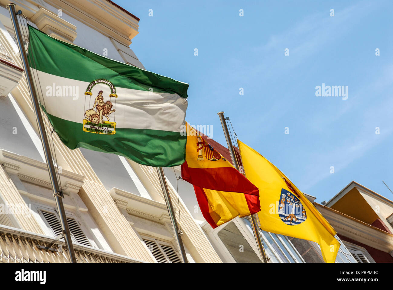 Flag of Andalusia province,( Green & White strip) Spanish national flag (  Red & yellow) and City of Cadiz flag ( Yellow with crown) in the old city o  Stock Photo - Alamy