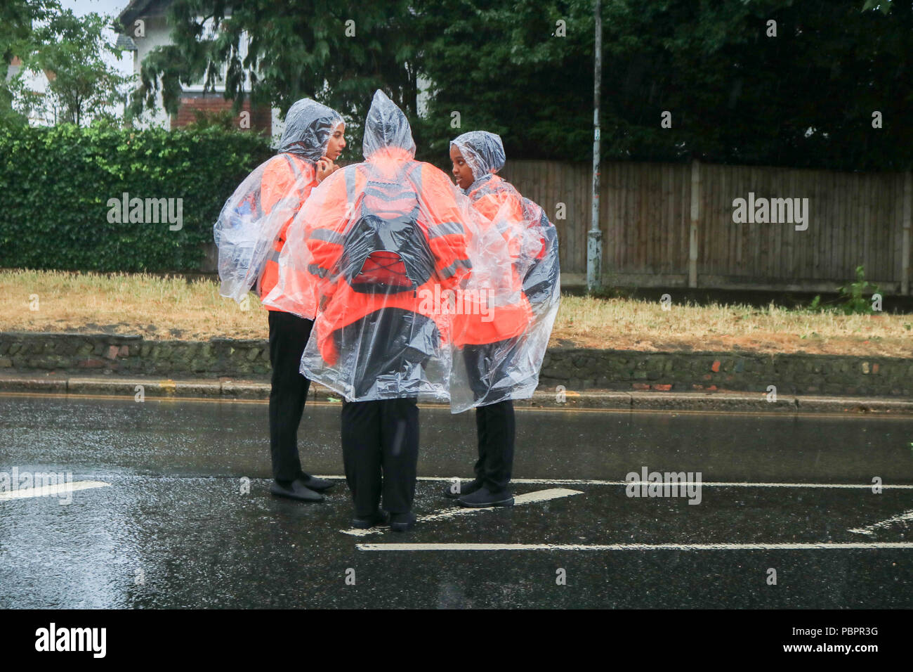 London UK. 29th July 2018. Race stewards dressed in  rain ponchos for the Prudential London Surrey 100 classic event in wet conditions as the rains come down. The Prudential ride Celebrates  the legacy for cycling created by the London 2012 Olympic and Paralympic Games and follows a 100-mile route on closed roads through the capital and into Surrey’s  countryside Credit: amer ghazzal/Alamy Live News Stock Photo