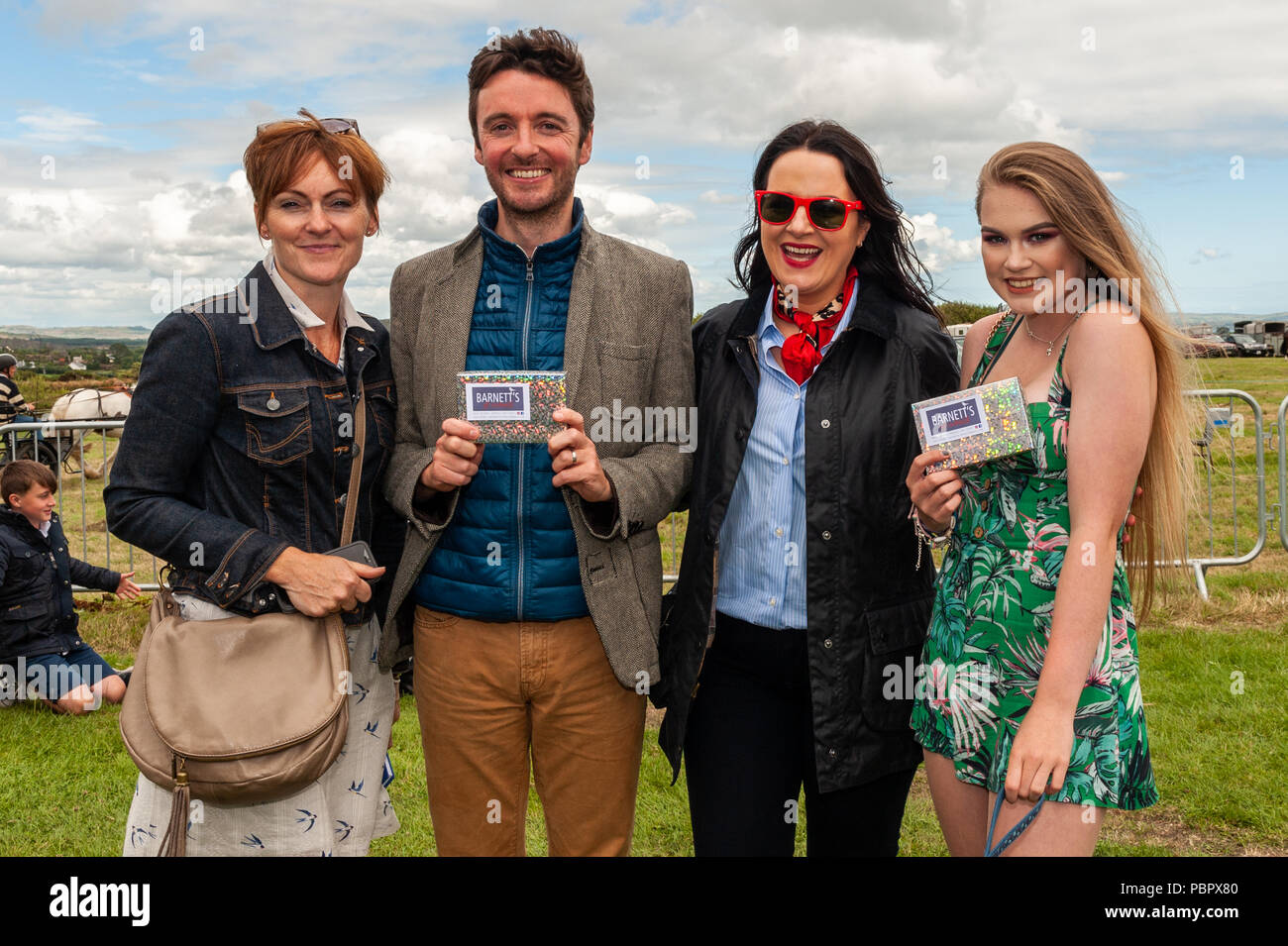 Schull, West Cork, Ireland. 29th July, 2018. Schull Agricultural Show is underway in blazing sunshine with hundreds of people attending. Beauty & Fashion Journalist and TV Presenter Triona McCarthy judged the Best Dressed Lady and Gentleman at the show. The winners, John Heffernan from Ardfield and Annie O'Brien from Kilvrounge, are pictured with competition sponsor Miriam Pyburn and judge Triona McCarthy. Credit: Andy Gibson/Alamy Live News. Stock Photo