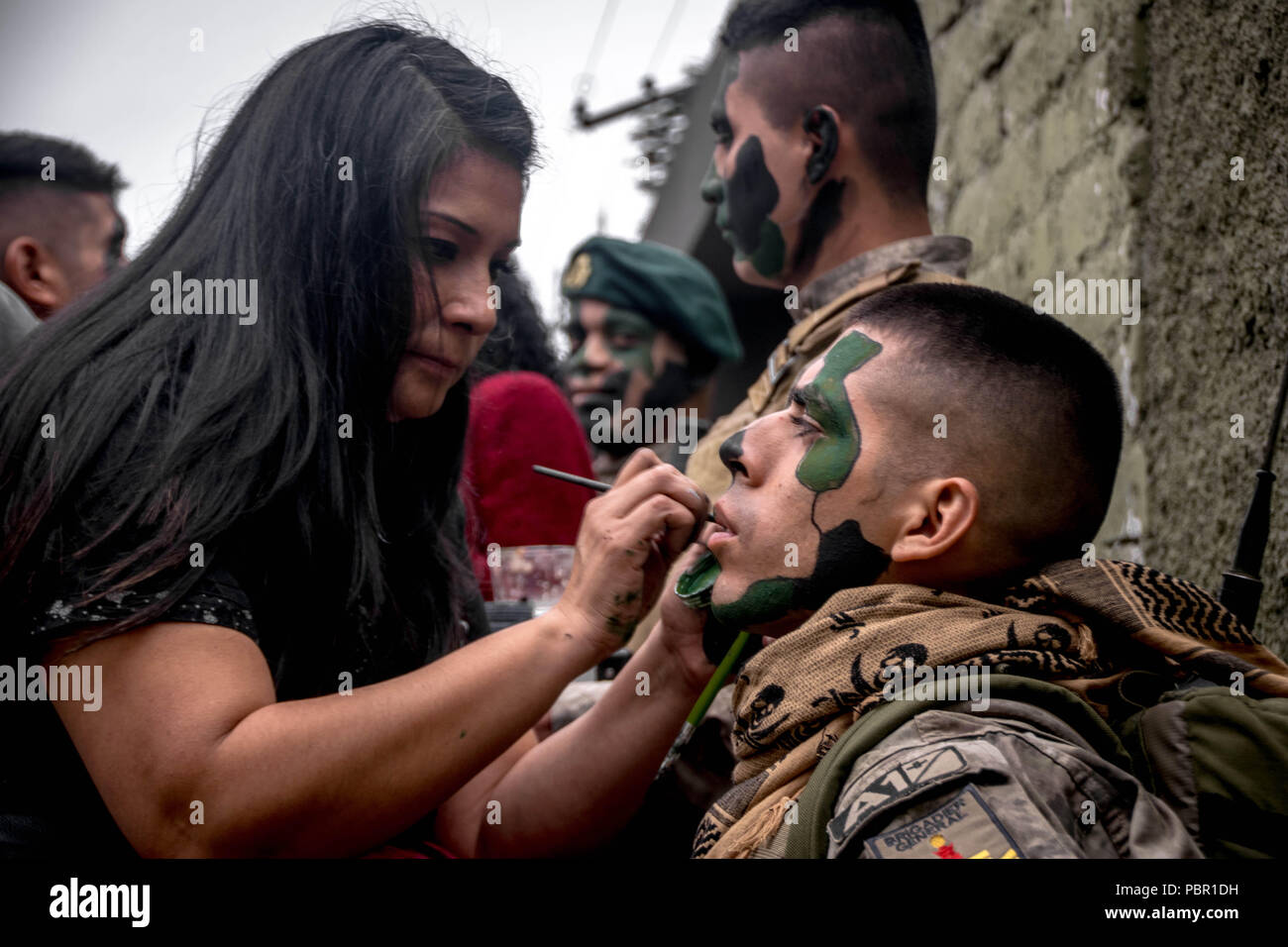 Lima, Lima Region, Peru. 29th July, 2018. A woman seen painting a camouflage on a Peruvian soldier's face.Members of Peru's armed forces, coastguard, search & rescue, and police march in full uniform during the country's Gran Parada Militar. This parade always occurs the day after Peru's Independence Day marking the official end of festivities across the nation. Credit: Jason Sheil/SOPA Images/ZUMA Wire/Alamy Live News Stock Photo