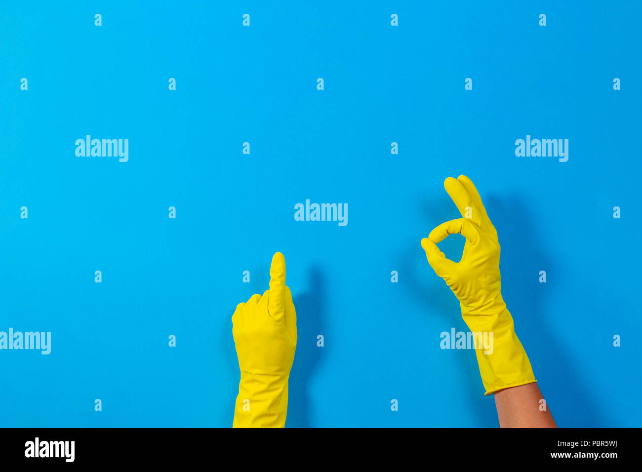 Woman hands with yellow rubber gloves making a gesture meaning ok and
