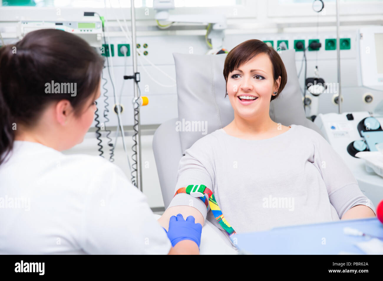 Nurse in hospital checking access at woman blood donor Stock Photo