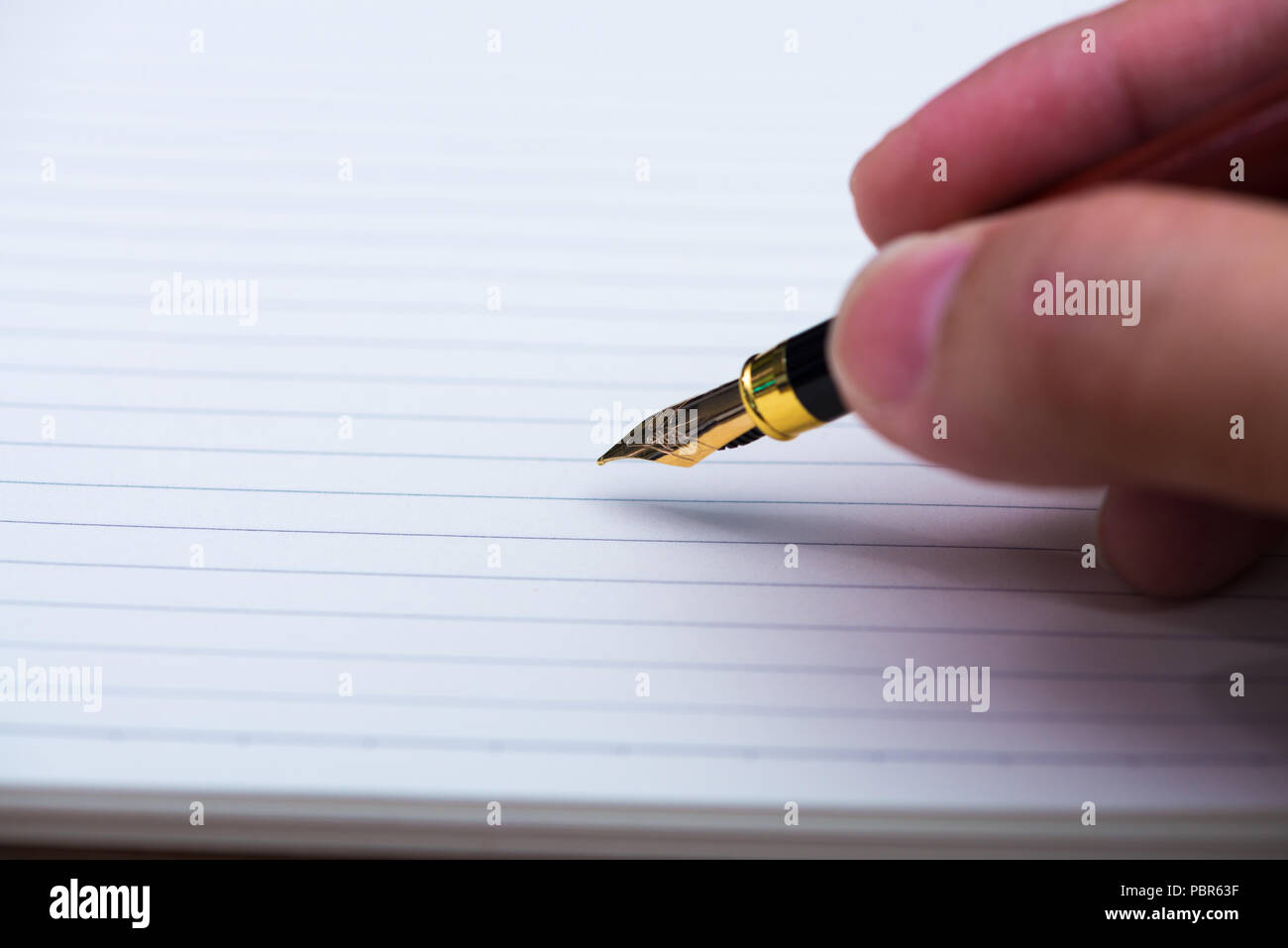 Man hand writing with fountain pen or ink pen with notebook paper on