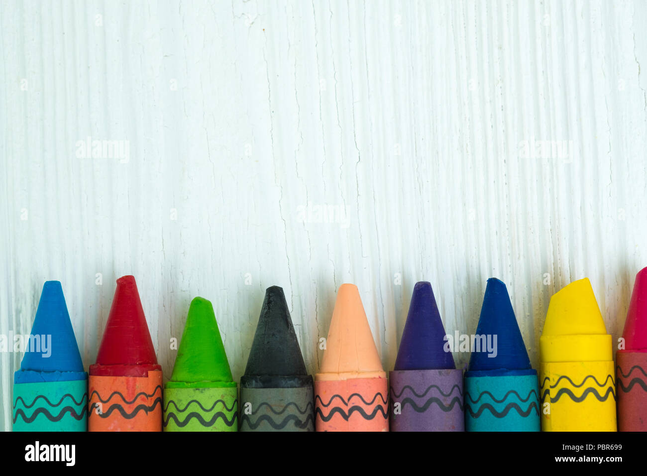 Colourful wax crayons pencils on white wood table with copy space for ...