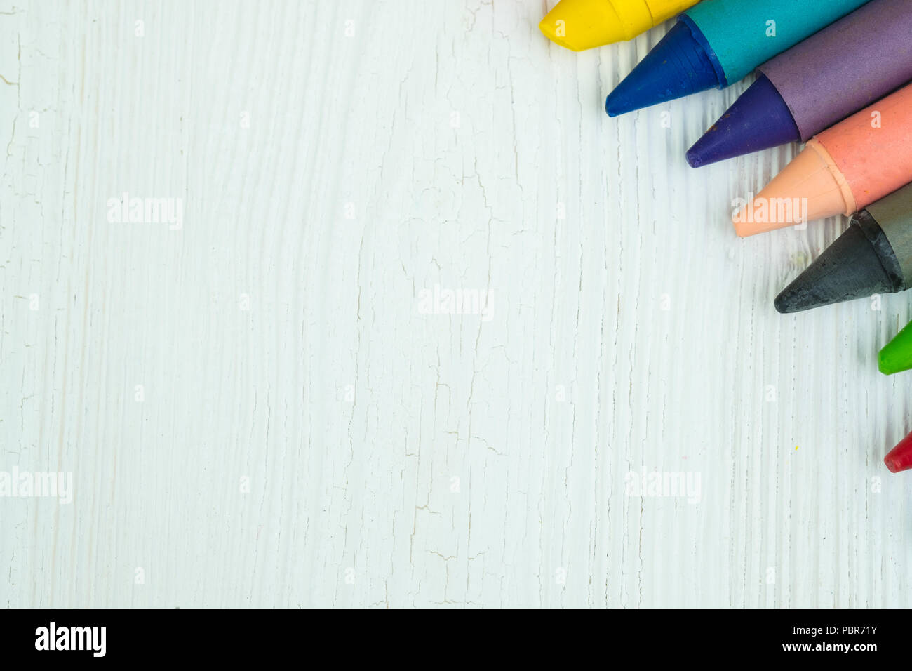 Colourful wax crayons pencils on white wood table with copy space for ...