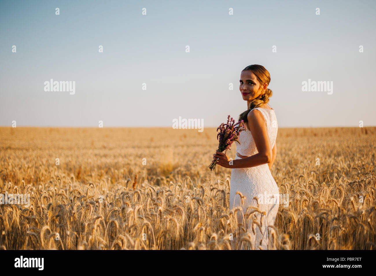 Bride shooting with a bouquet in a field Stock Photo