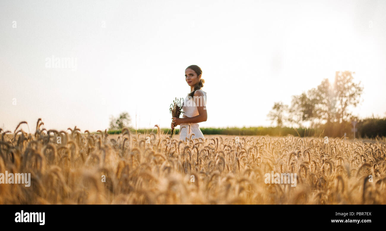 Bride shooting with a bouquet in a field Stock Photo