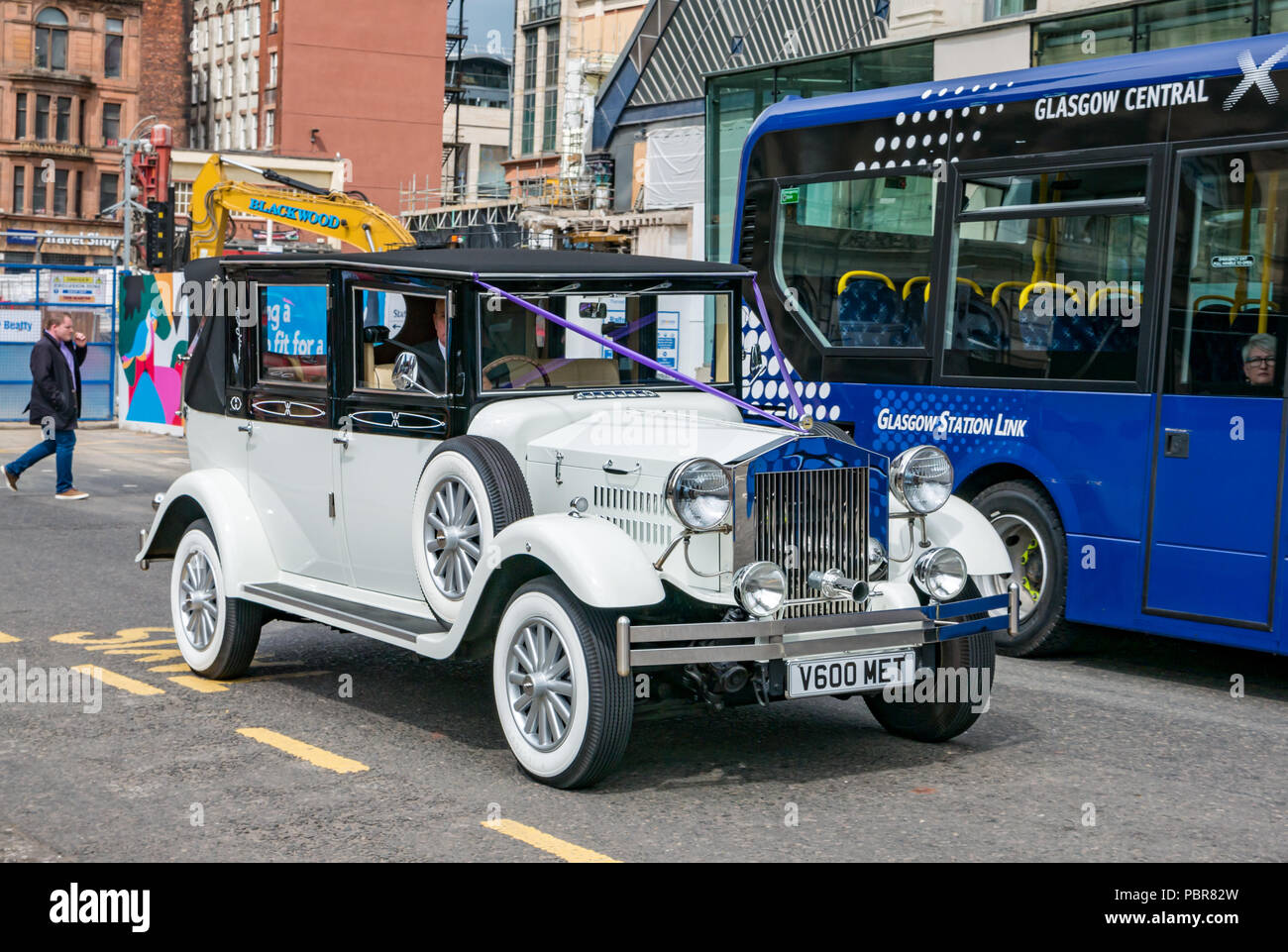 White Imperial Viscount 1930s vintage style 7 seater launderlette car decorated for wedding next to Queen Street station and bus, George Square, Glasgow, Scotland, UK Stock Photo