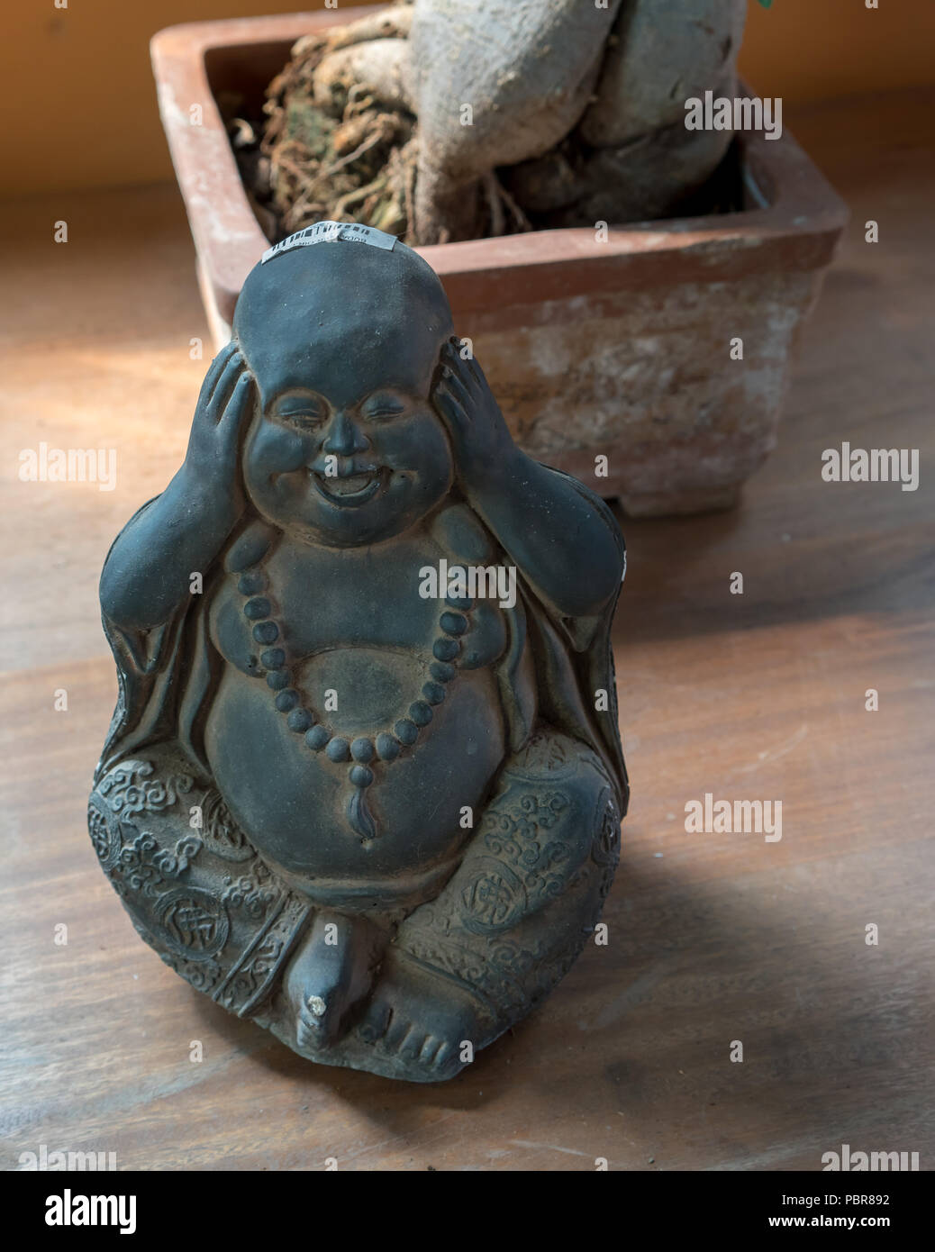 A Buddha or bodhisattva figure laughing with his hand covering his ears Stock Photo Alamy