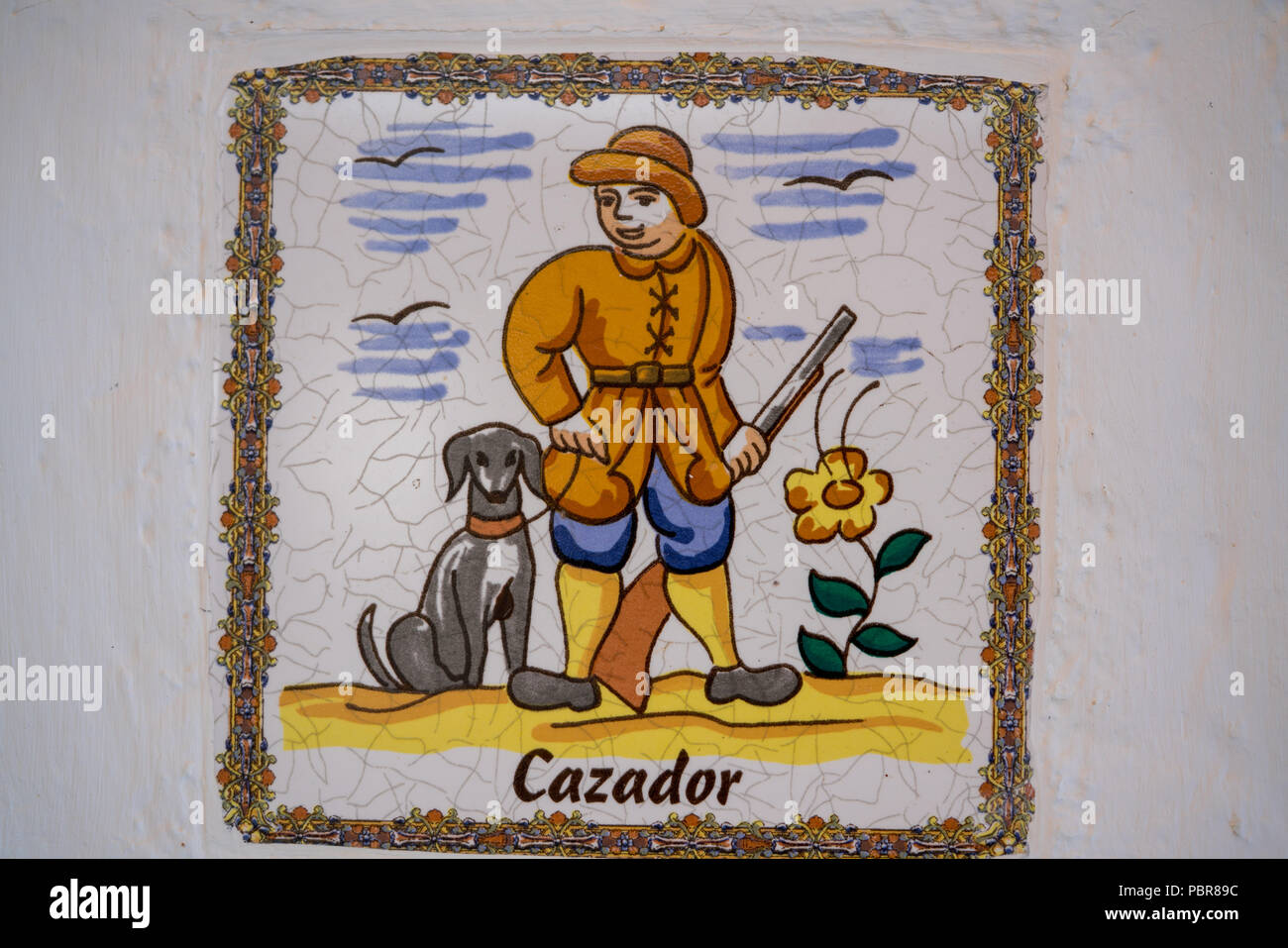 A single ceramic tile depicting a Spanish hunter with dog and gun Stock Photo