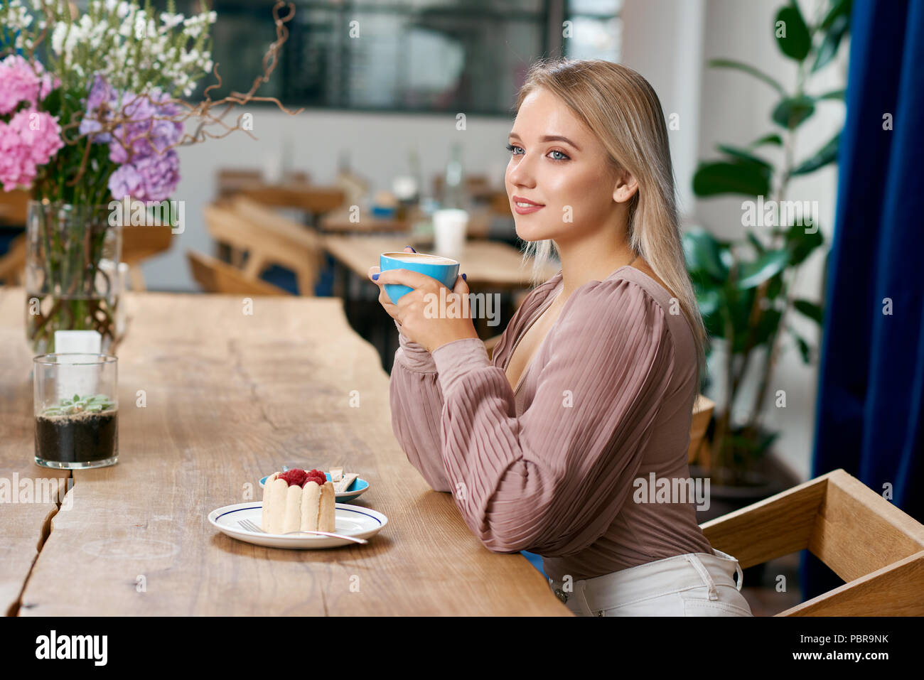 Beatiful Girl With Blonde Hair And Blue Eyes Drinking Coffee In