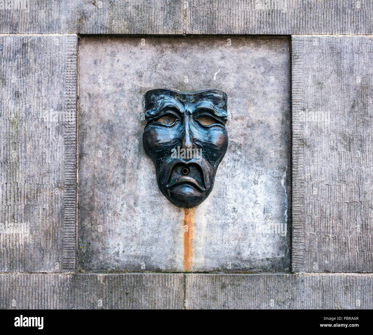 Close up of Fringe symbol comedy mask of sad face on Well Head street fountain outside Fringe box office, Royal Mile, Edinburgh, Scotland, UK Stock Photo