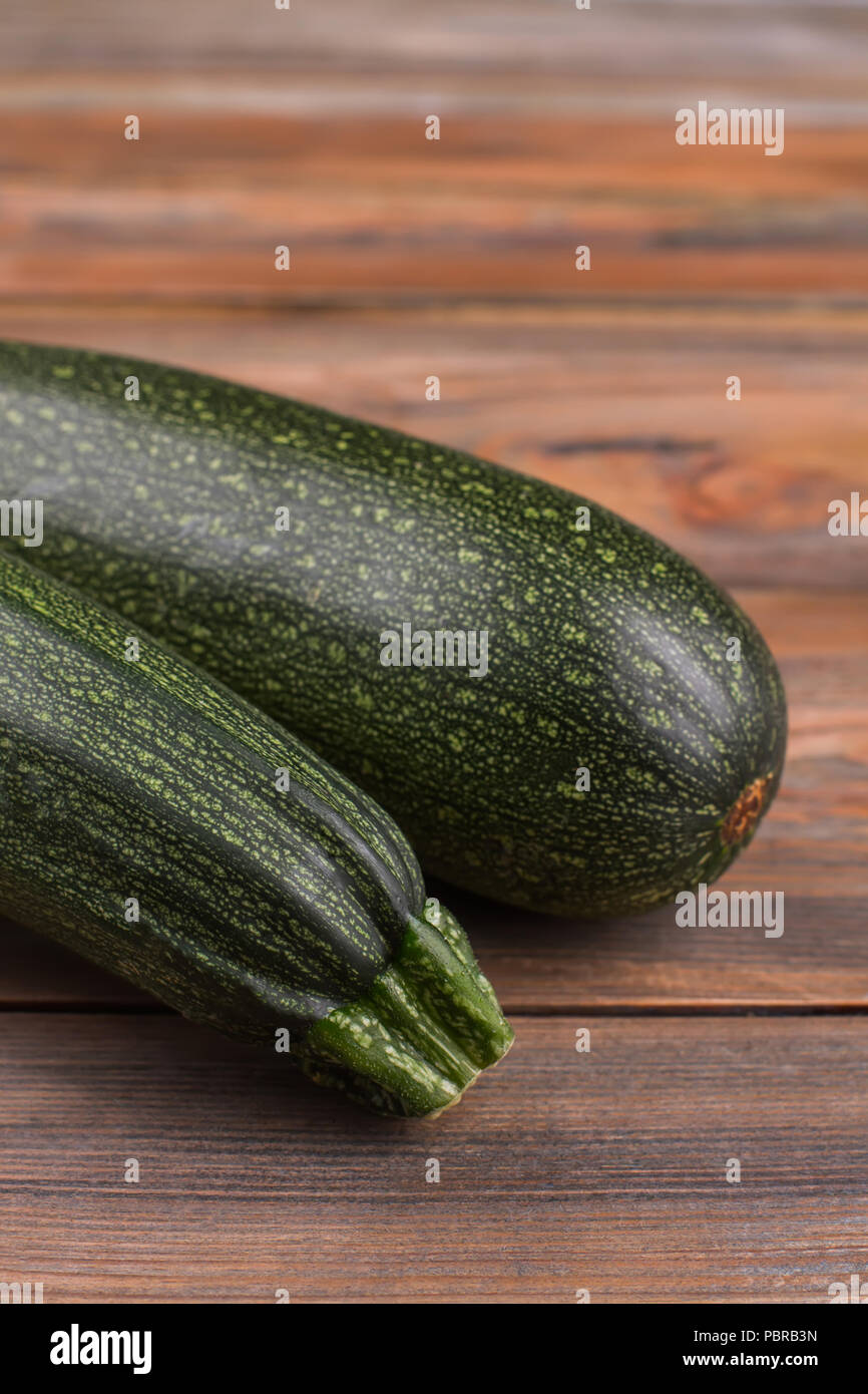 Raven zucchini close up. Brown wooden background. Stock Photo