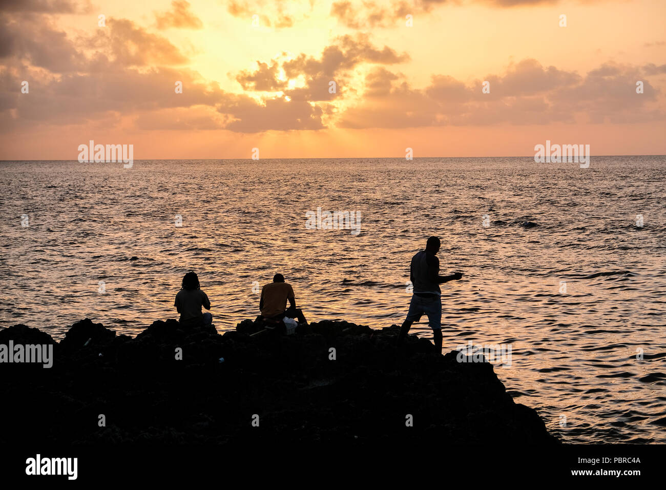Caymanians people fishing from shore at sunset Cayman Island Stock Photo