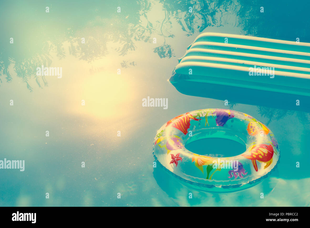 Inflated buoy and mattress floating on water of a swimming pool. Summer and holidays concept with ciopy space. Stock Photo