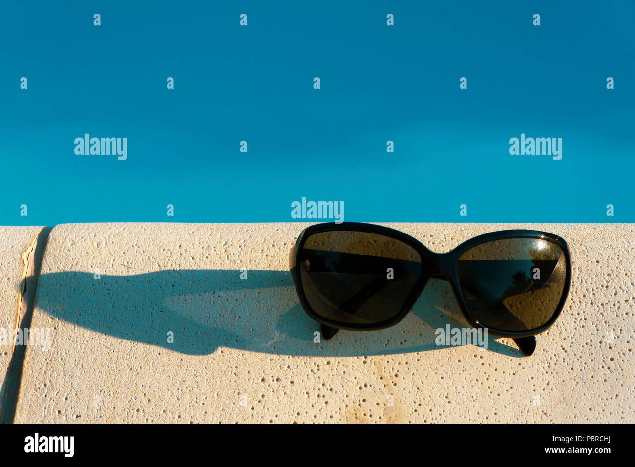 Sunglasses on the edge of a swimming pool. Summer concept with copy ...