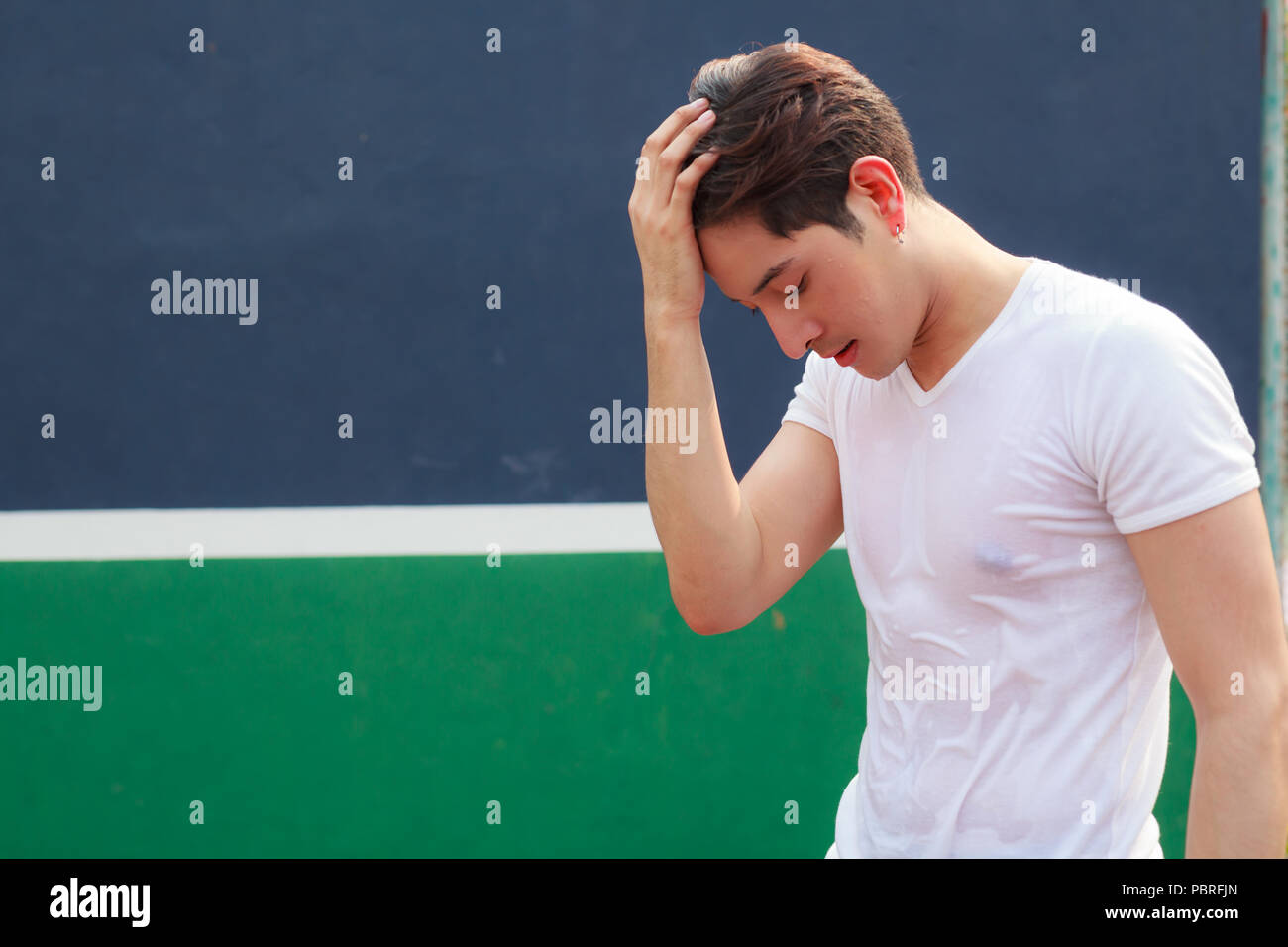 young handsome athlete man pausing after exercise with sweat on his face on sport club background Stock Photo