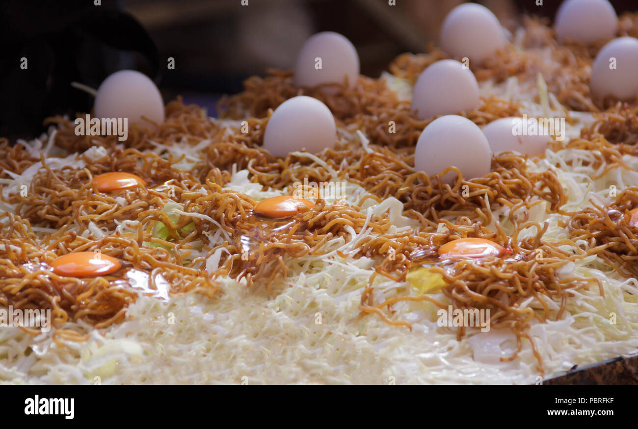 yakisoba (Japanese fried noodles with bite-sized pork, vegetables and flavored with sauce, salt and pepper is prepared on hot pan Stock Photo