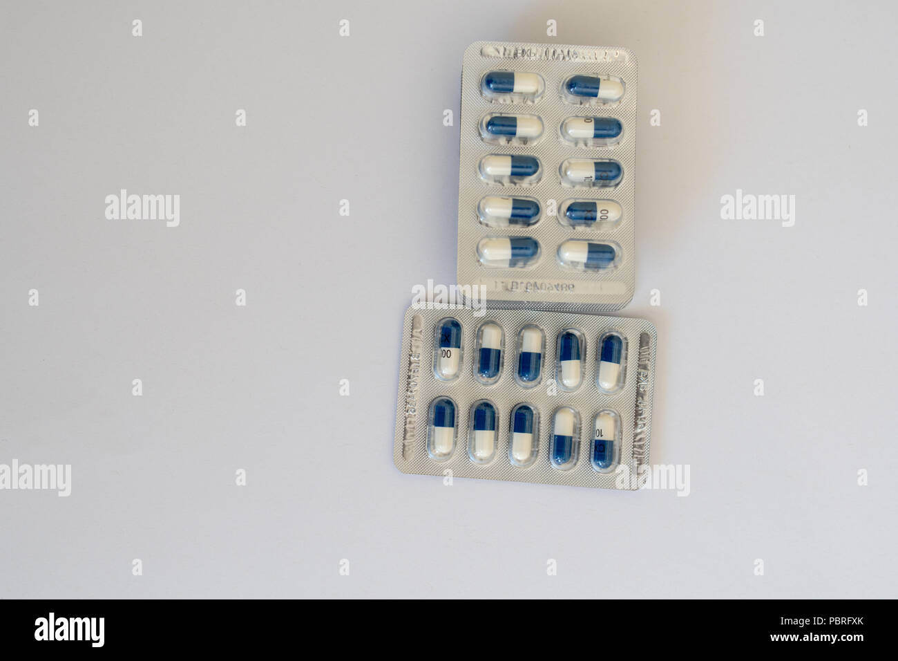 An overhead shot of several blister packs of blue and white capsules Stock Photo