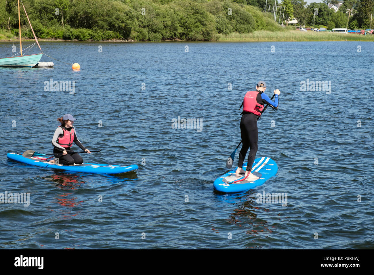People wearing wetsuits and life jackets paddleboarding on Derwent