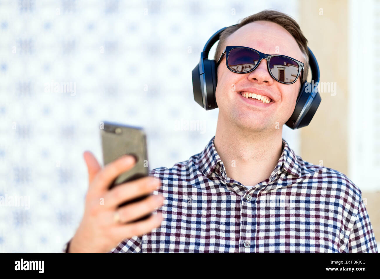 Young man with modern, wireless bluetooth-headphones enjoying the music from his smartphone Stock Photo