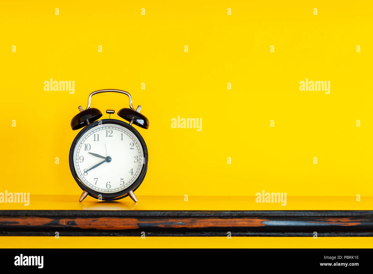 Alarm clock on yellow background with copy space. Stock Photo