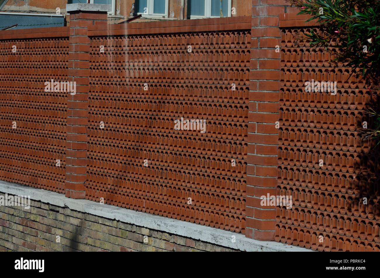 Red coloured compound wall (made of terracotta tiles) of a house ...