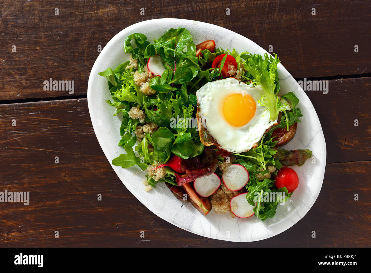 Plate fresh salad with quinoa and fried egg on wooden table. Healthy food clean eating Stock Photo
