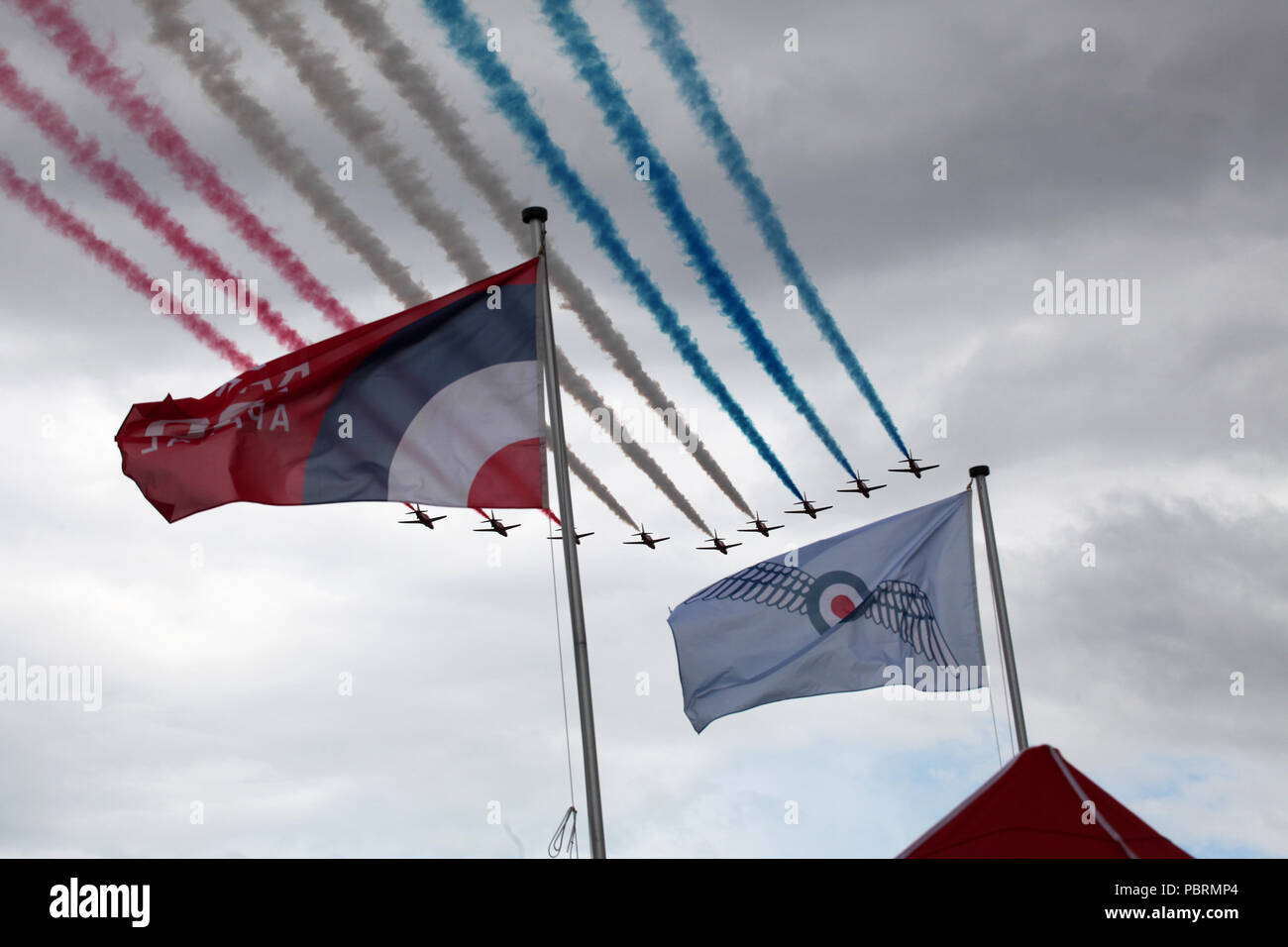 Framed by flags the Red Arrows make a flypast at Scotland's national airshow held at the national museum of flight, East Fortune near Edinburgh Stock Photo