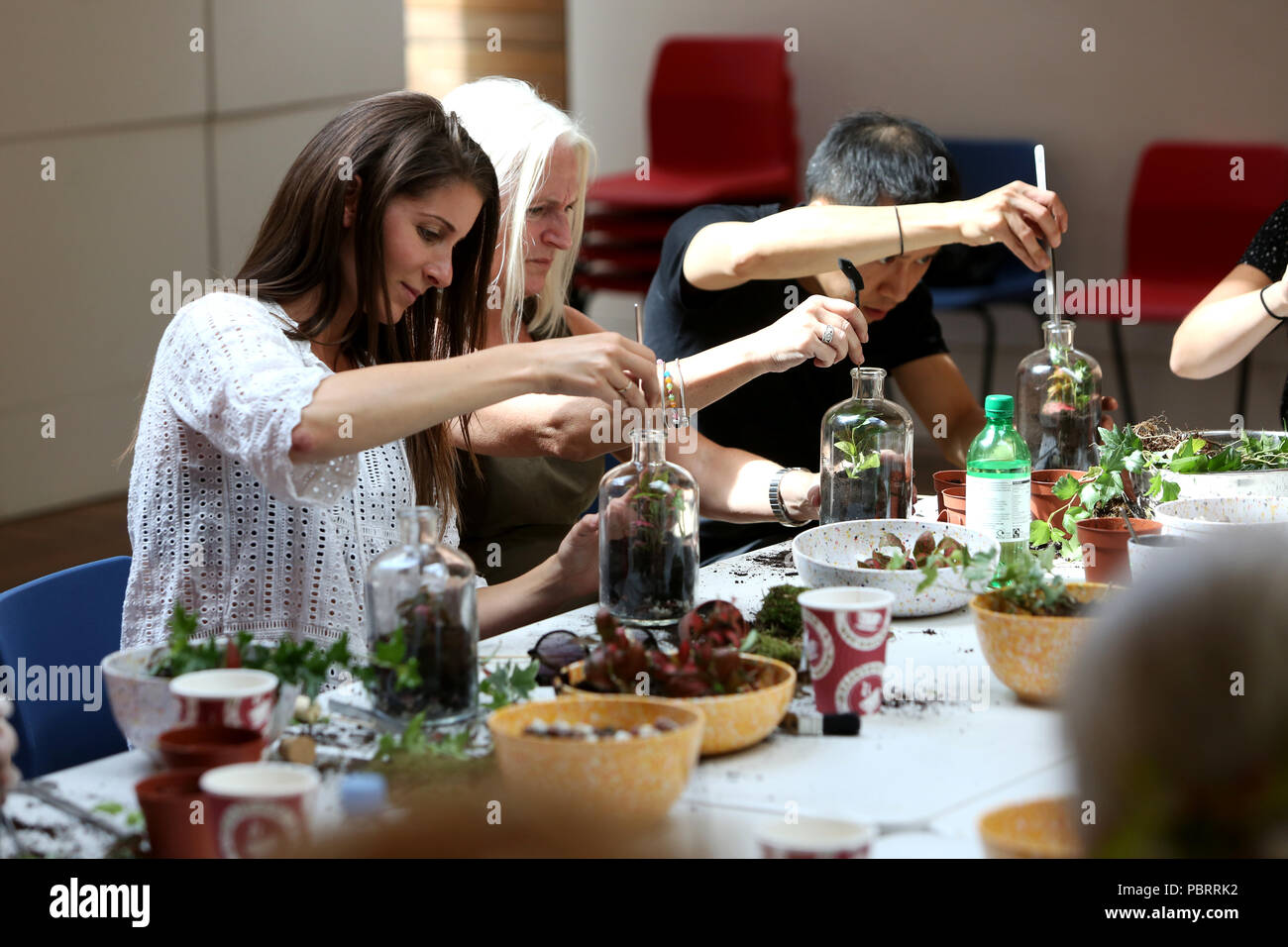 A group of people getting creative and designing and making their own Terrariums in Chichester, West Sussex, UK. Stock Photo