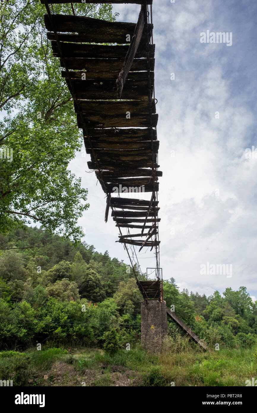 Broken remnants of a long abandoned old footbridge at Can Quel de Baix, near Oix in the Catalonian Pyrenees, Spain Stock Photo