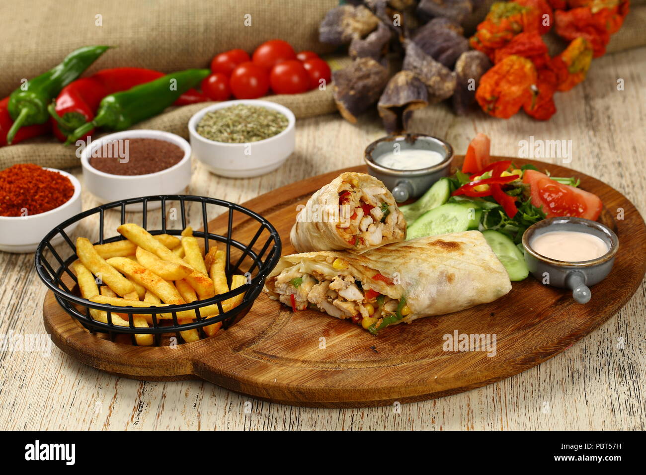 Fried chicken stuffed tortilla wrap sandwich with vegetables and french fries Stock Photo