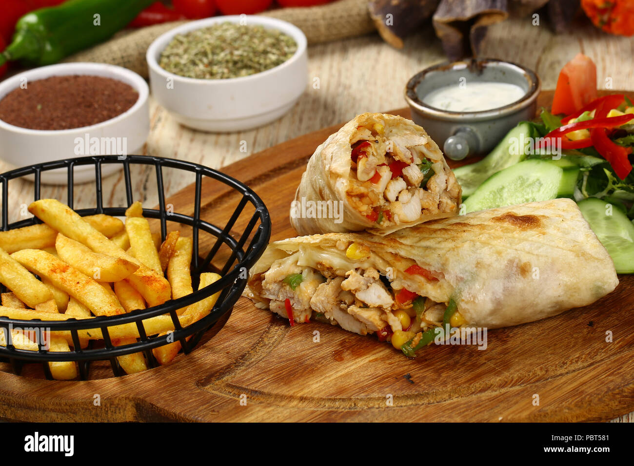 Fried chicken stuffed tortilla wrap sandwich with vegetables and french fries Stock Photo