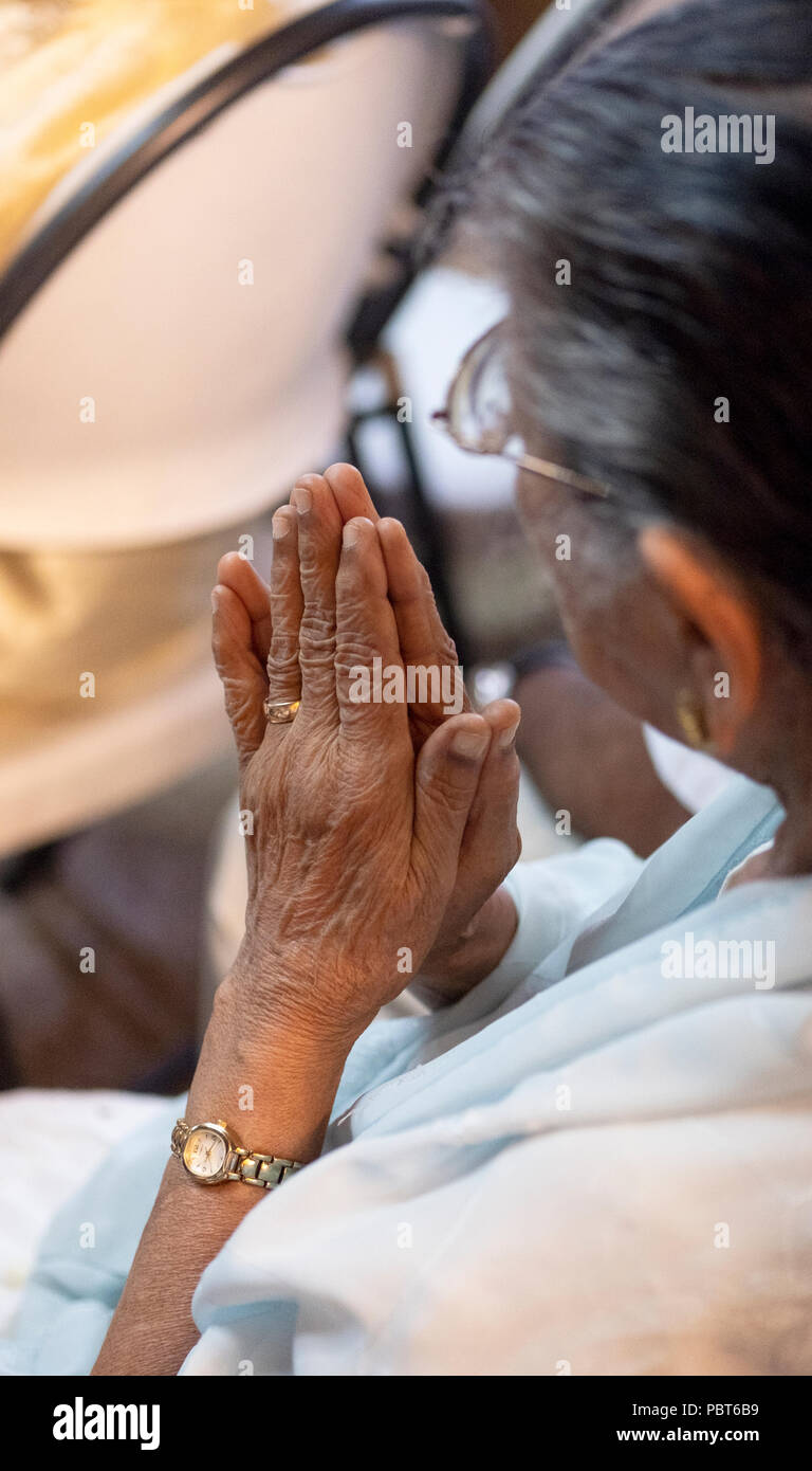 A close up photo of an older Hindu woman's hands clasped together during prayer and meditation. In South Ozone Park, Queens, New York. Stock Photo