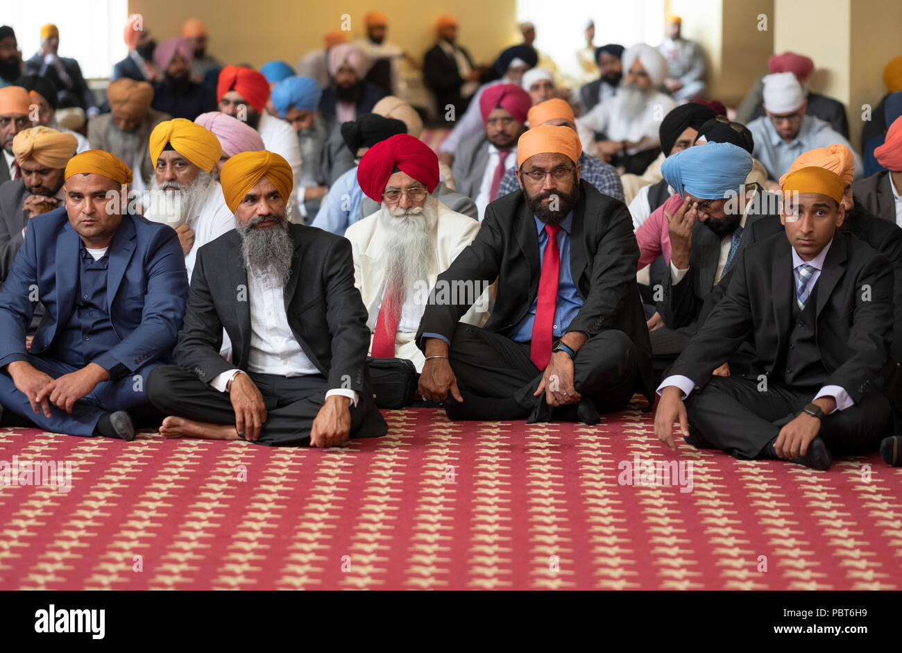 Male guests including the groom's father (white suit) at a Sikh wedding in Richmond Hill, Queens, New York. Stock Photo