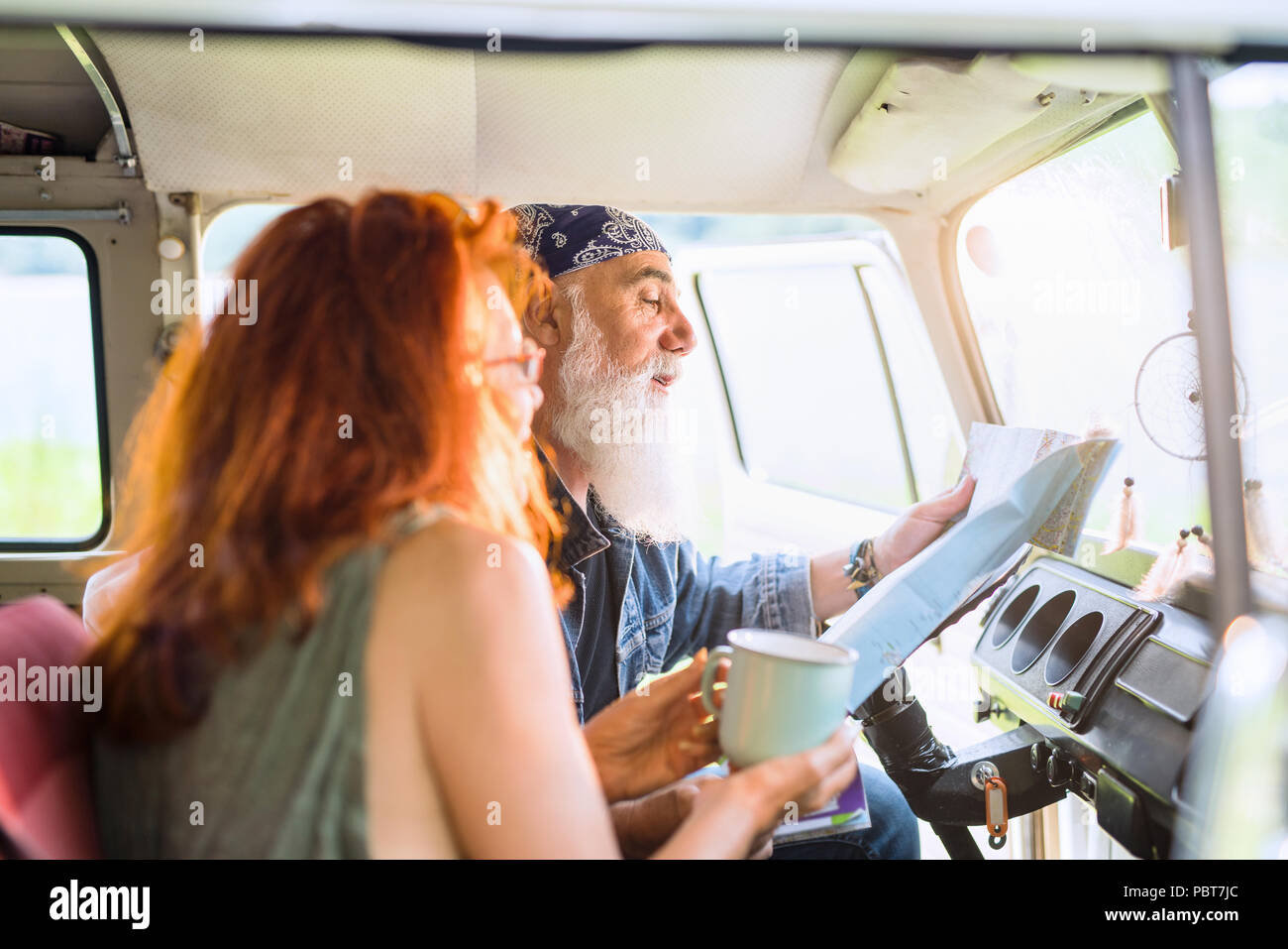 A trendy senior couple on vacation in a van Stock Photo