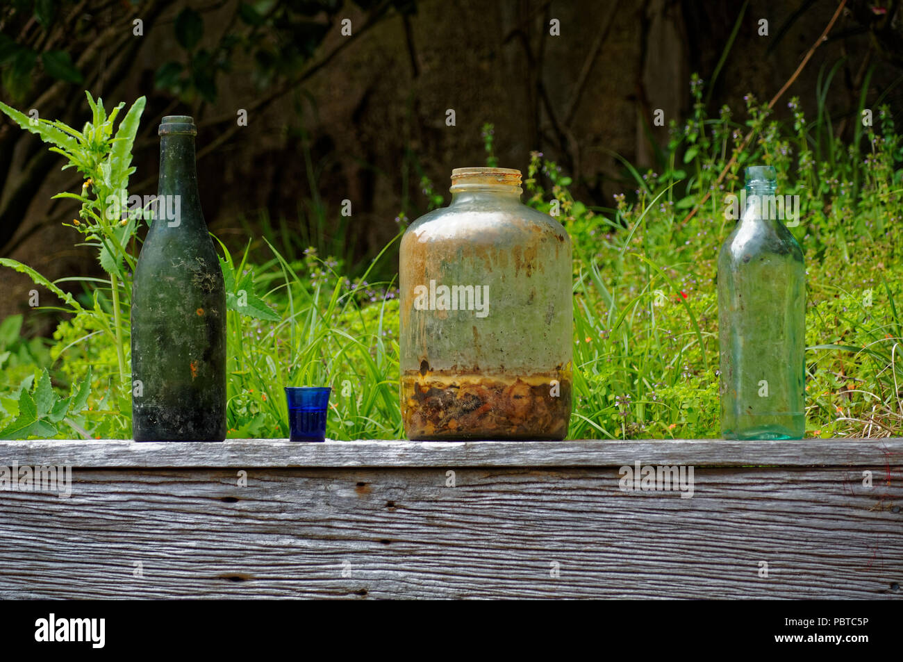 Old bottles and jars discarded on a wooden garden fence Stock Photo