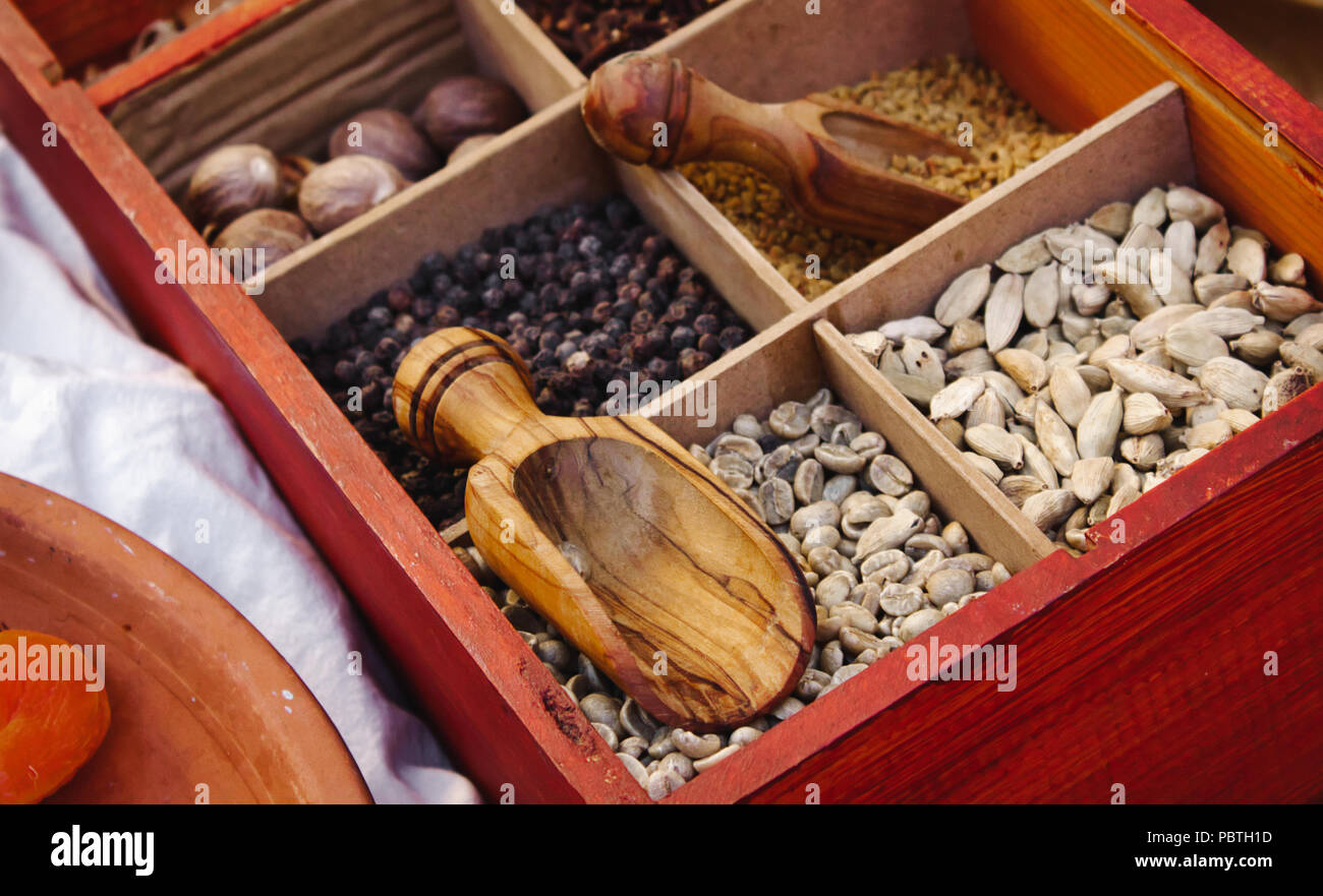 Various exotic spices and condiments in boxed compartments used in eastern cooking with wooden serving spoons Stock Photo