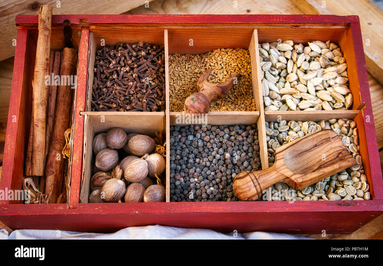 Various spices and condiments in boxed compartments used in eastern cooking with wooden serving spoons Stock Photo