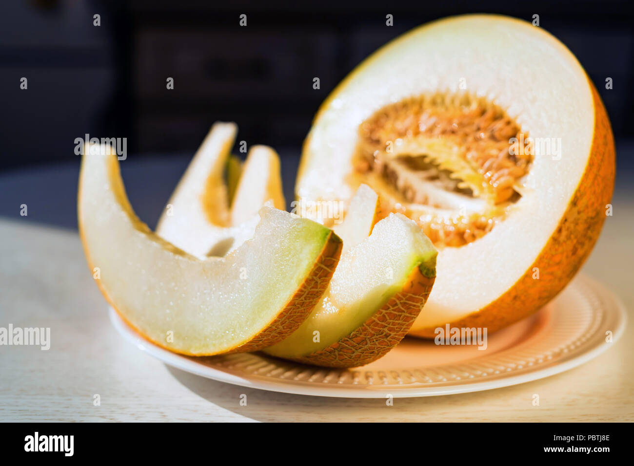 Half melon and melon slices on white plate close Stock Photo