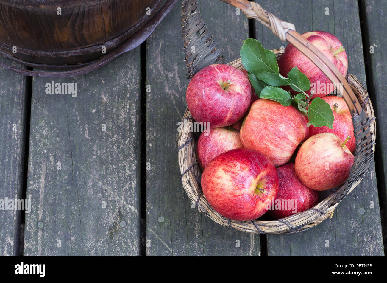 Overhead view of ripe red apples in a basket on a rustic wooden surface ...