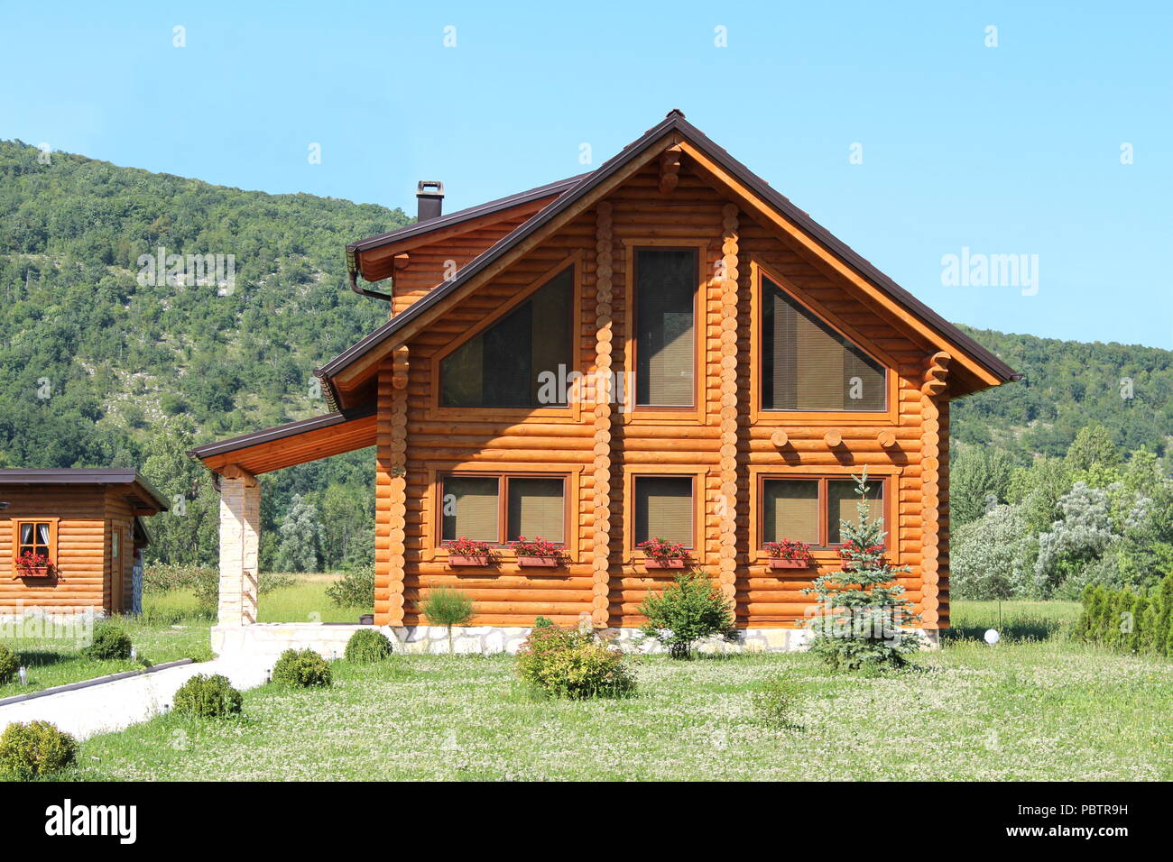 Newly Built Wooden Log Cabin House With Large Windows And Stone