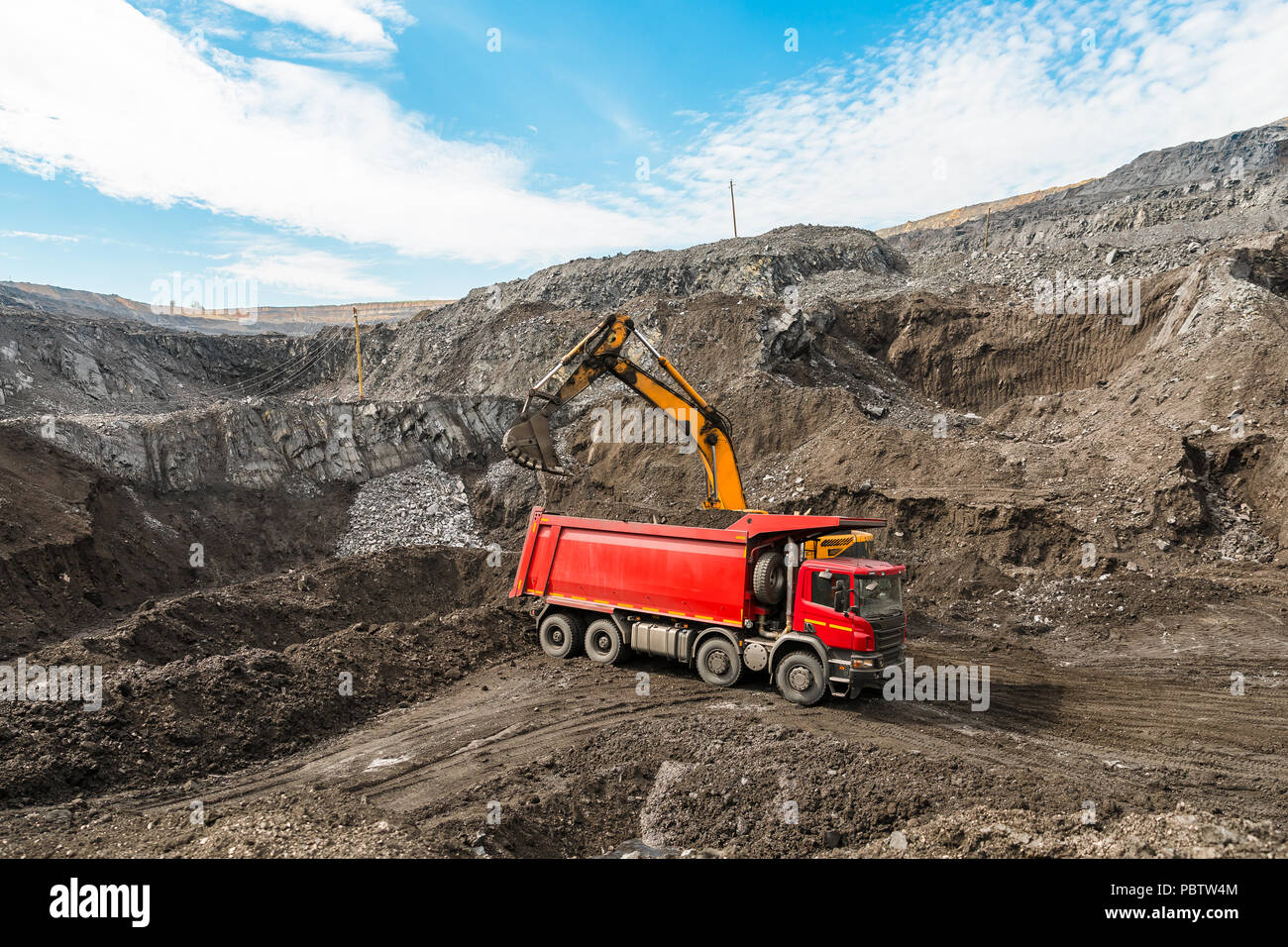 Large quarry dump truck. Loading the rock in dumper. Loading coal into body truck. Production useful minerals. Mining truck mining machinery, to transport coal from open-pit as the coal production. Stock Photo
